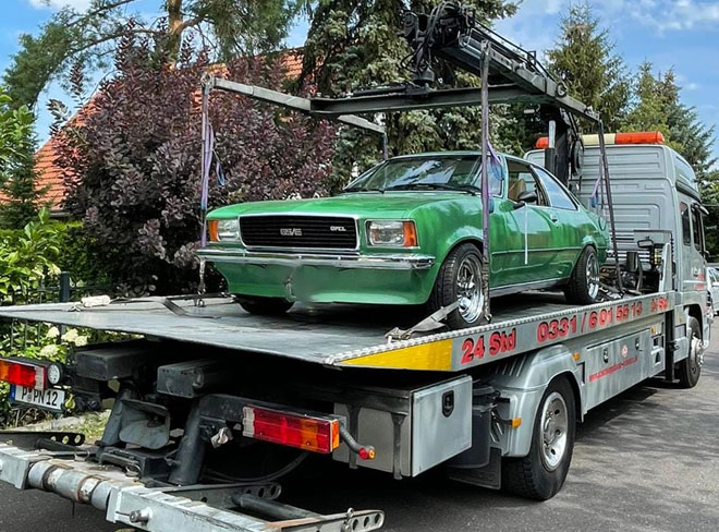 green classic car on tow truck