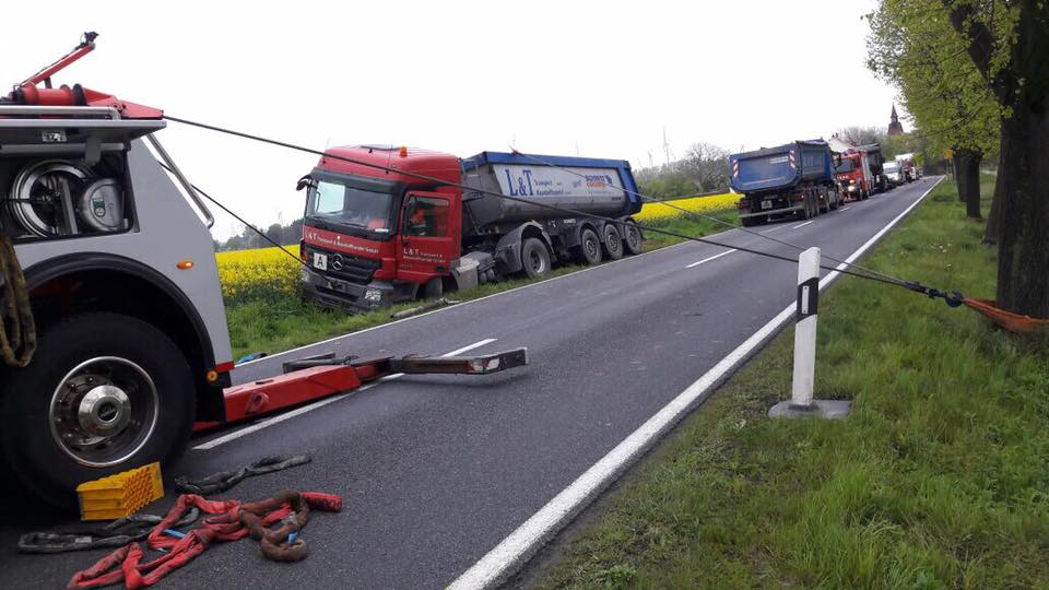 Truck recovery after engine failure – heavy-duty tow truck pulling an articulated lorry out of a roadside ditch